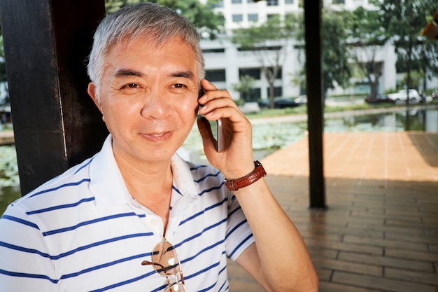 Homem chinês sênior falando ao telefone