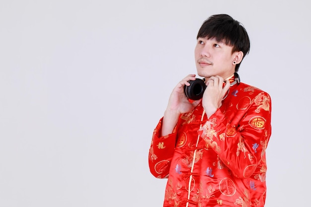 Homem chinês sortudo na tradicional camisa mandarim sorri e se deleita por se tornar cultural no feliz feriado da celebração da prosperidade para o ano novo lunar