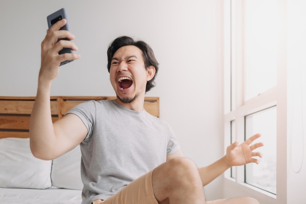 Homem chocado e feliz recebendo boas notícias do smartphone