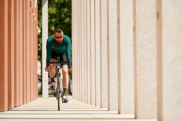 Homem ciclista andando de bicicleta esportiva de engrenagem fixa em dia ensolarado em uma cidade