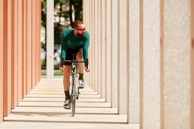 Homem ciclista montando bicicleta esportiva de engrenagem fixa em um dia ensolarado em uma cidade