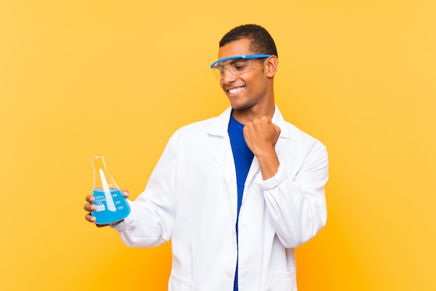 Homem científico segurando um balão de laboratório sobre parede comemorando uma vitória