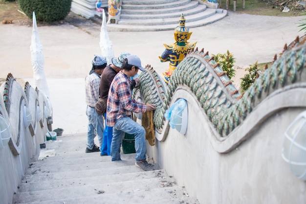 Homem colando ladrilhos de cerâmica na escada Naga na construção do templo Escada Naga na Tailândia