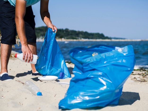 Foto homem, colecionar, desperdício, lixo plástico, de, a, praia, e, pôr, em, azul, bolsa lixo