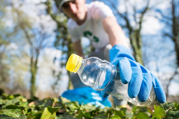 Homem coletando lixo plástico em um parque poluído