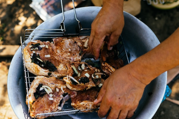 Homem coloca carne na grelha para grelhar