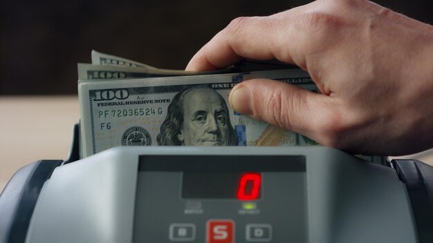 Homem colocando dólares contador de perto máquina de cálculo de notas americanas