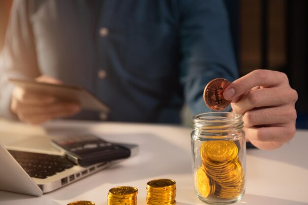 Homem colocando moedas em vidro para economizar dinheiro conceito finanças e contabilidade em escritório em casa