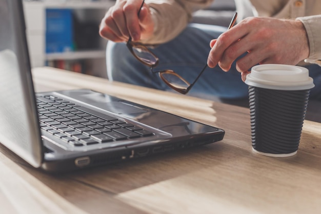 Homem colocando óculos no laptop para fazer uma pequena pausa cansado após um longo trabalho ou ficando nervoso