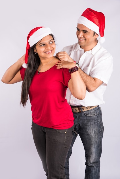 Homem colocando um colar no pescoço de uma mulher na época do natal, um homem indiano presenteando o colar para a esposa da namorada no natal, um casal asiático e um colar de presentes