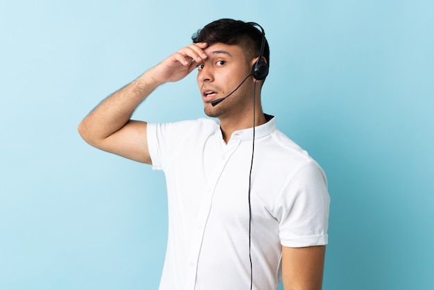 Homem colombiano de telemarketing trabalhando com fone de ouvido isolado, fazendo gesto de surpresa enquanto olha para o lado