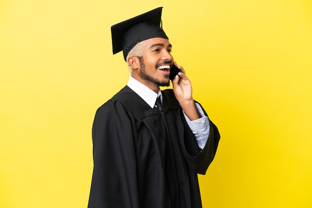 Homem colombiano jovem universitário isolado em um fundo amarelo, conversando com o celular.