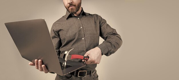 Homem com a barba cortada, quebra de visão, laptop batendo no computador com dano de hardware de fundo cinza de martelo