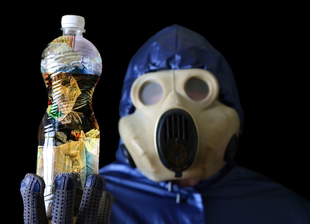 Homem com a máscara de gás segurando uma garrafa de plástico com água suja. poluição ambiental. desastre ecológico.