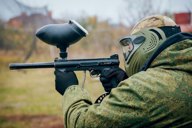 Homem com arma jogando paintball. ao ar livre