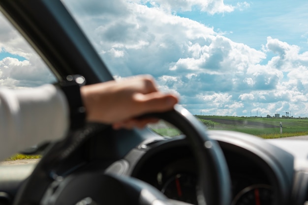 Homem com as mãos no volante, dia ensolarado e nublado, cópia espaço