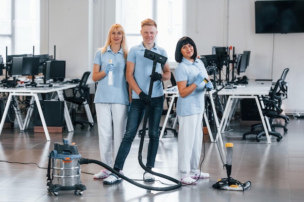 Foto homem com aspirador grupo de trabalhadores limpa escritório moderno juntos durante o dia