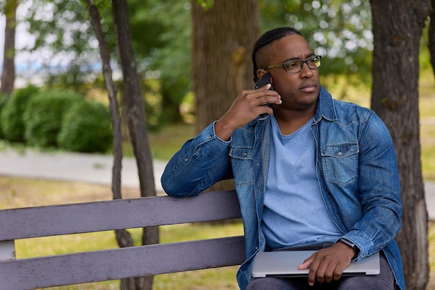 Homem com banco de laptop no parque da cidade está tendo uma conversa séria com o fornecedor