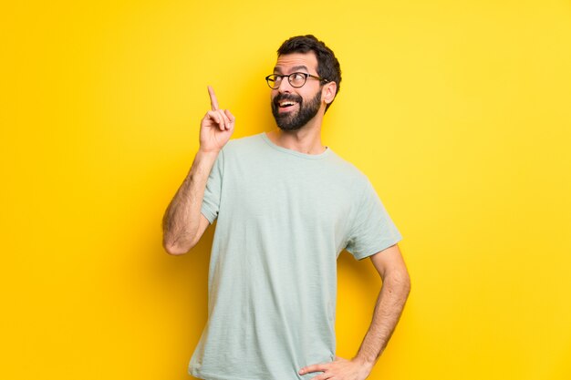 Homem com barba e camisa verde com a intenção de perceber a solução, enquanto levanta um dedo para cima