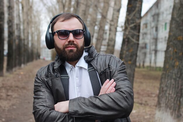 Homem com barba e fones de ouvido no parque