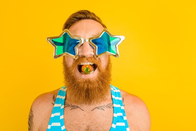 Homem com barba e óculos de sol comendo morango