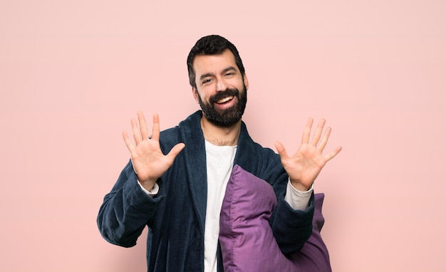 Homem, com, barba, em, pijamas, contagem, dez, com, dedos, sobre, isolado, fundo rosa