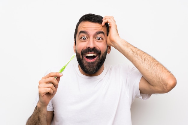 Homem com barba, escovar os dentes sobre branco isolado, fazendo o gesto de surpresa