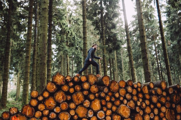 Homem com barba passa por madeira na floresta