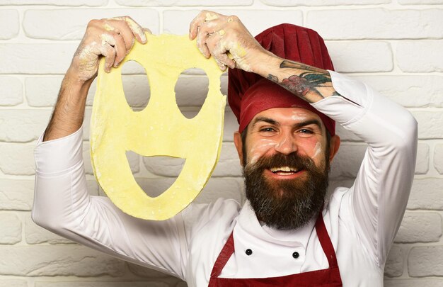 Foto homem com barba segura massa enrolada com smiley cortado