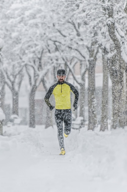 Homem com barba treina correndo na neve em um inverno frio
