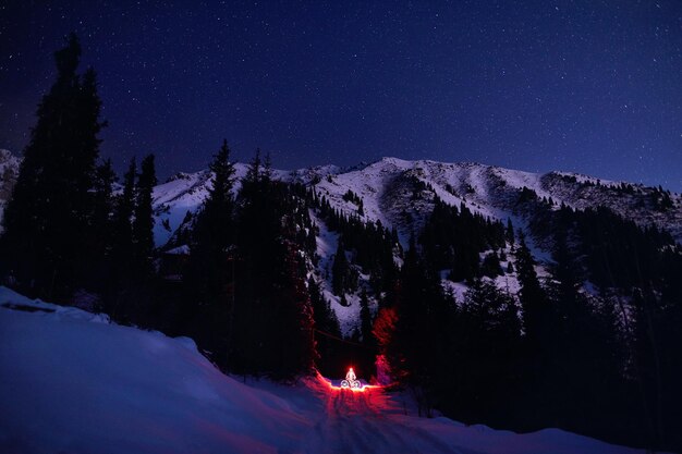 Homem com bicicleta em Winter Mountains à noite