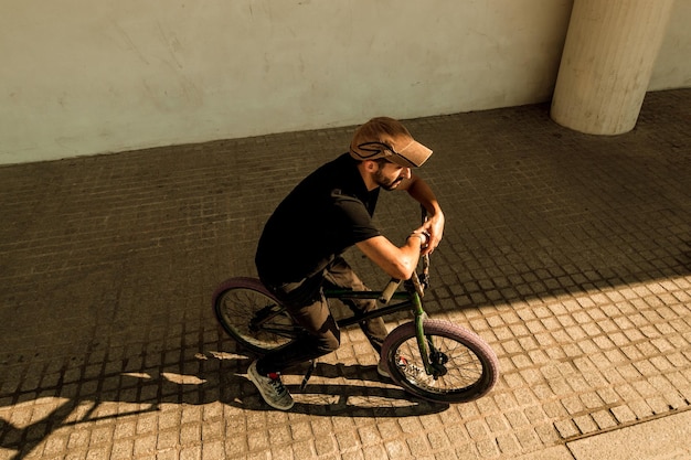 Homem com bicicleta na calçada contra a parede