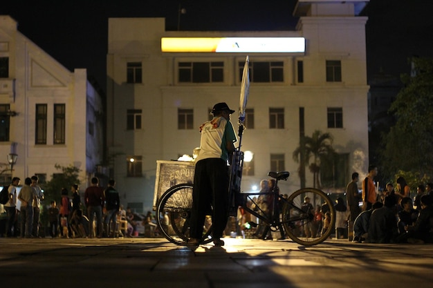 Foto homem com bicicleta na rua da cidade à noite
