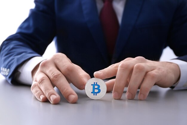 Foto homem com bitcoin prata sentado à mesa closeup