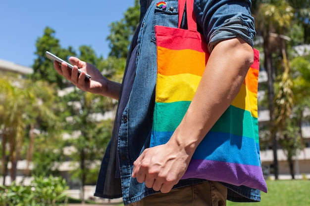Homem com bolsa reutilizável arco-íris e emblema lgbt mês do orgulho