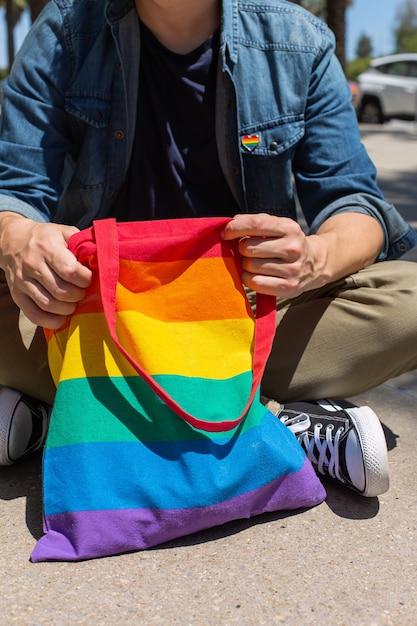 Homem com bolsa reutilizável arco-íris e emblema lgbt mês do orgulho