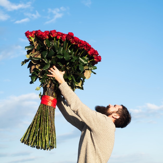 Homem com buquê de flores de rosas homem barbudo segura um grande buquê de rosas vermelhas em casamento