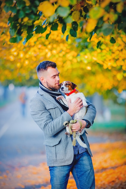 Homem com cachorro andando no beco de temporada outono.