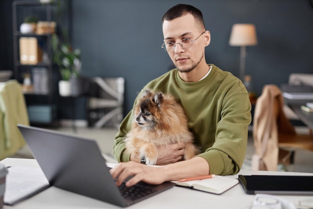 Homem com cachorro trabalhando em escritório amigável a animais de estimação