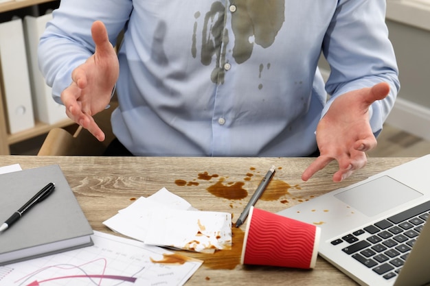 Homem com café derramado sobre seu local de trabalho e closeup de camisa