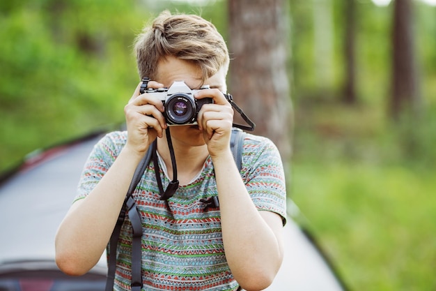 Homem com câmera fotográfica ao ar livre com floresta de verão no fundo
