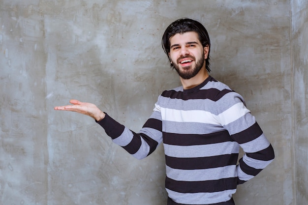 Homem com camisa listrada mostrando algo na mão