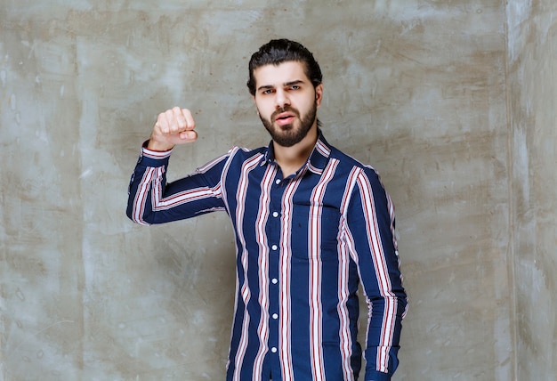 Homem com camisa listrada, mostrando os punhos e se sentindo forte.