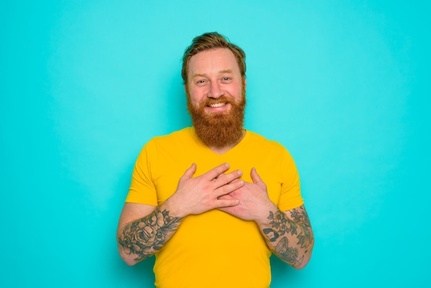 Homem com camiseta amarela e barba está muito feliz