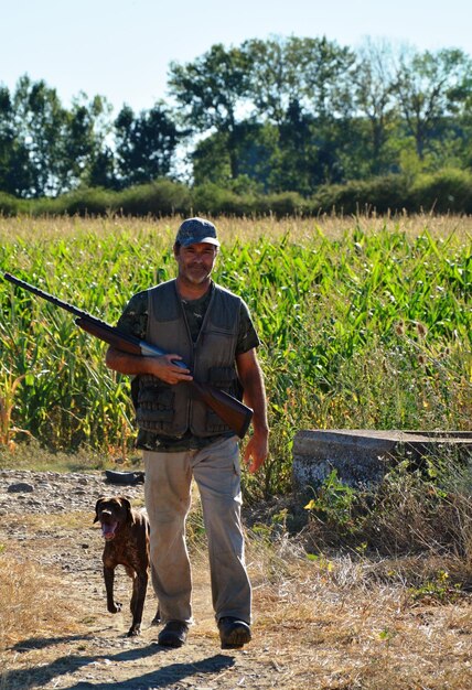 Homem com cão de pé junto a plantas