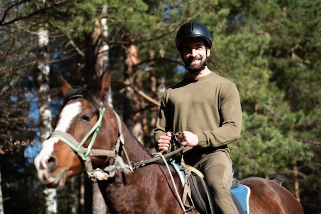 Homem com capacete andando a cavalo na floresta