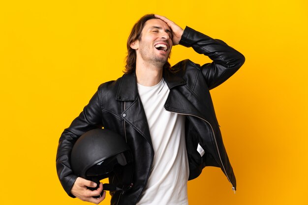 Foto homem com capacete de motociclista isolado na parede amarela e sorrindo muito