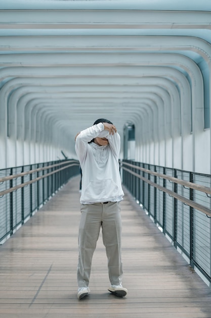 Foto homem com capuz posando na ponte de pedestres