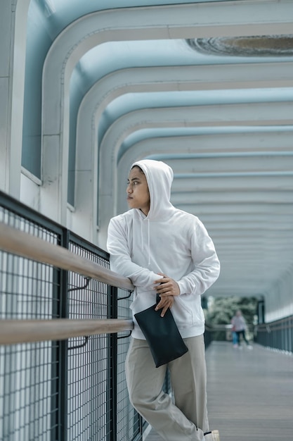 Homem com capuz posando na ponte de pedestres