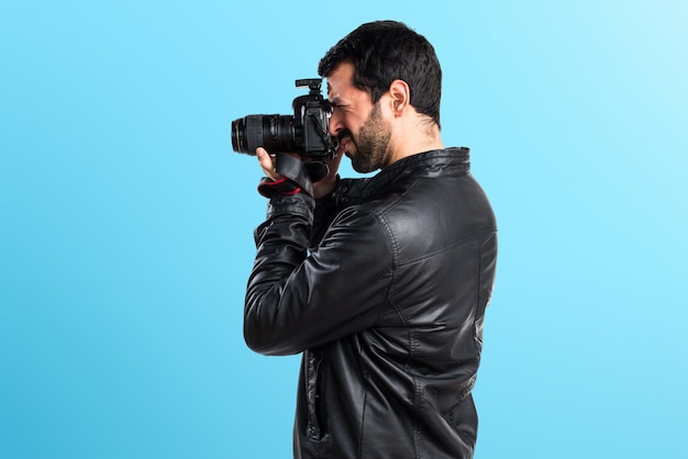 Homem com casaco de couro fotografando em fundo colorido